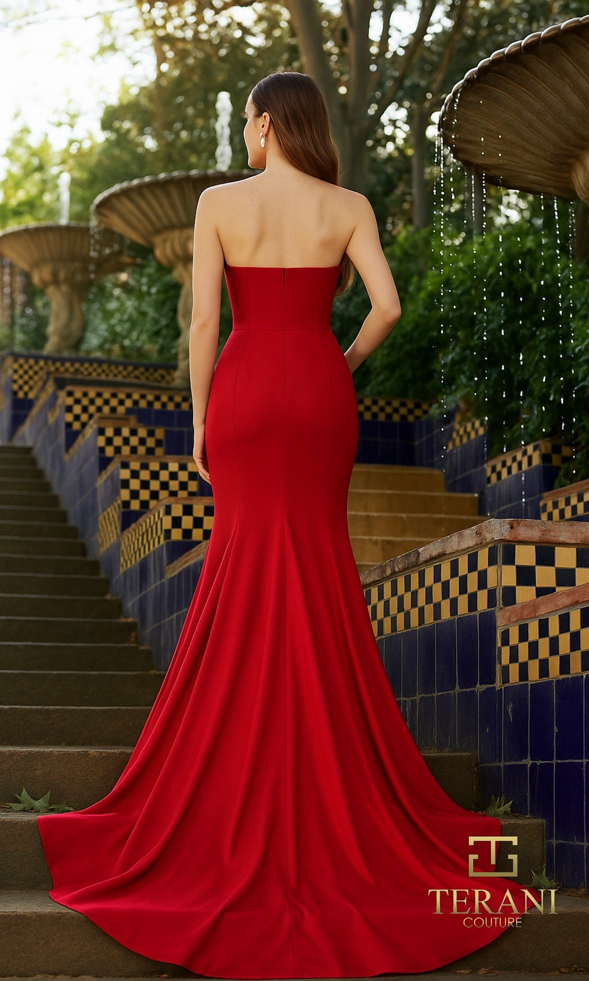A woman in a strapless, fitted Mikado gown stands by tiled fountains. The floor-length red dress flares at the bottom, adding elegance. Terani Couture logo appears, showcasing the Long Formal Dress: Terani 261P6624.
